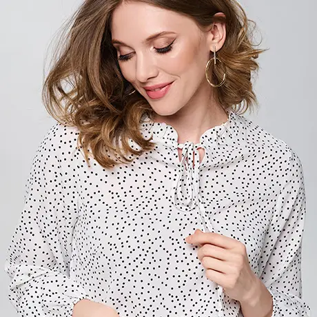 Smiling woman with wavy hair in a polka-dot blouse